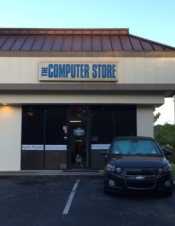 outside of the store with a basic sign saying The Computer Store and a dog peeking through the door