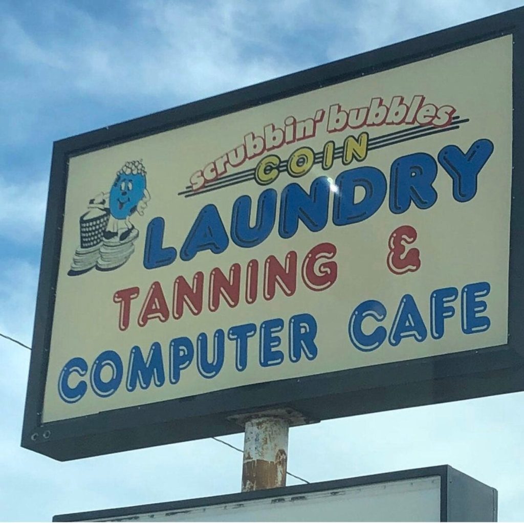 a sign saying Scrubbing Bubbles Coin Laundry Tanning & Computer Cafe