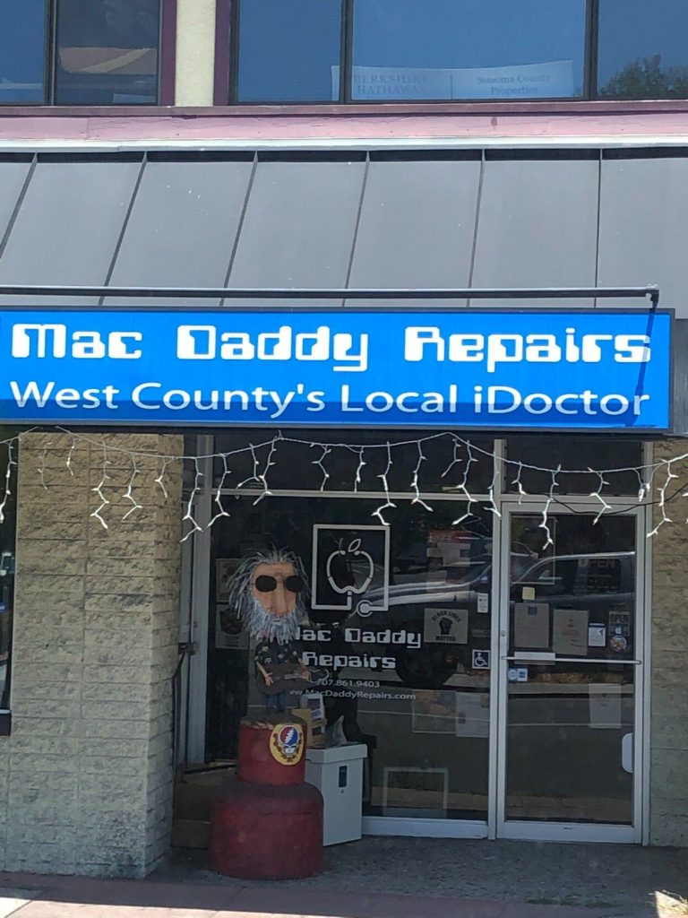 a statue that looks like Andy Garcia outside of a store called Mac Daddy Repairs