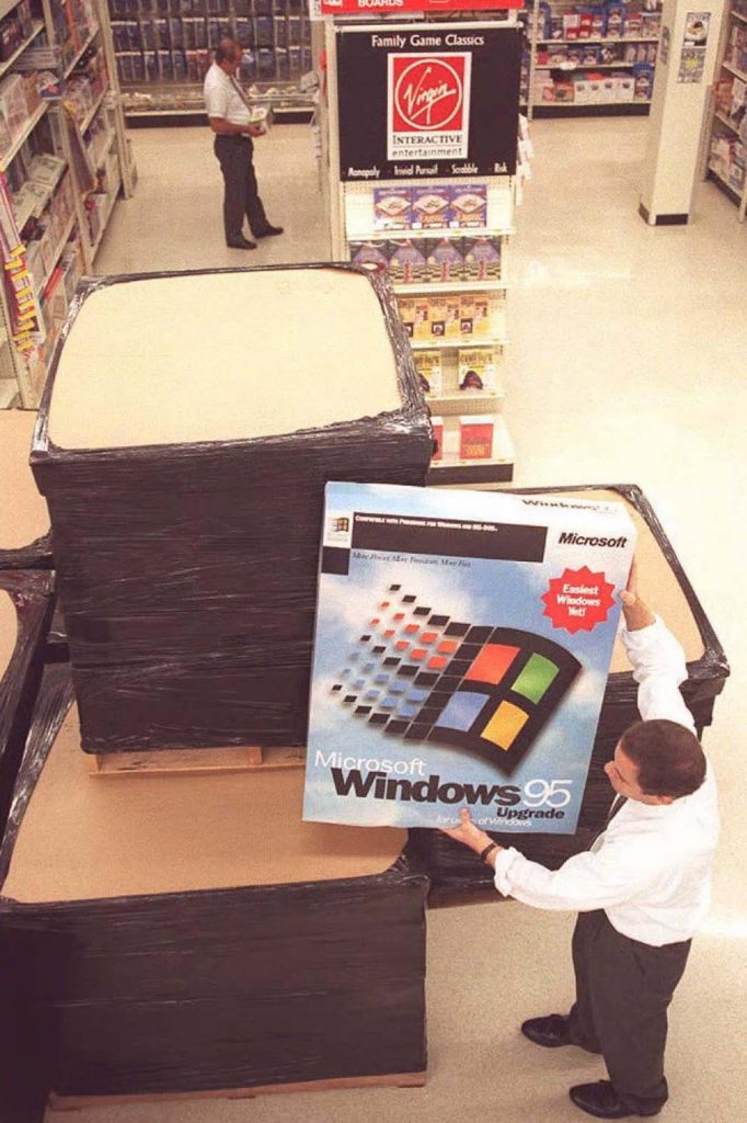 a man holding a giant Windows 95 box in a store