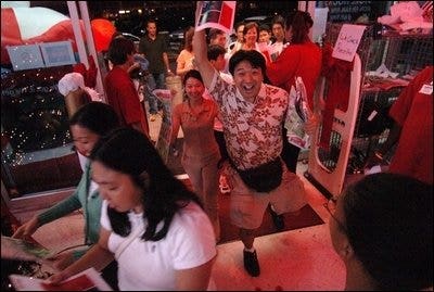 people walking through the doors of a compusa and a guy smiling at the camera