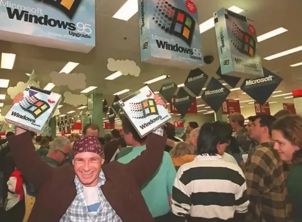 a guy holding two copies of windows 95 in a store
