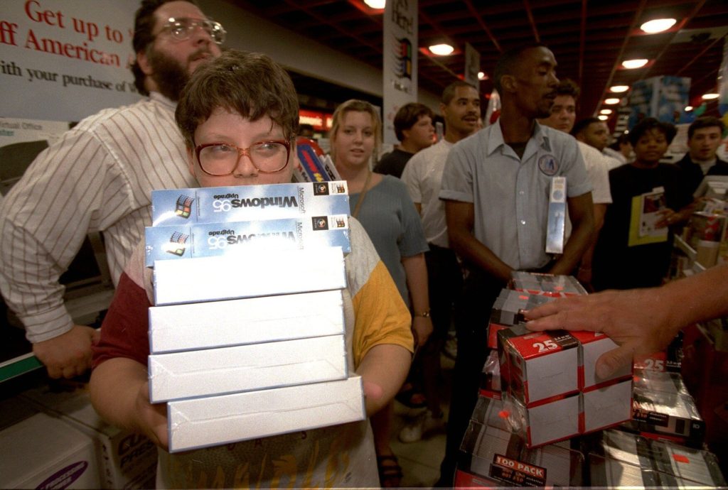 a kid holding a stack of windows 95 boxes