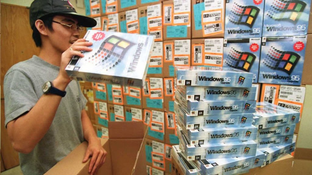 a guy pulling out windows 95 from a cardboard box and putting it in a stack